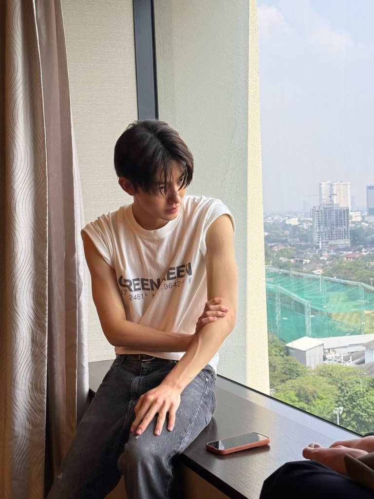 dominic duduk santai di jendela dengan kaos tanpa lengan